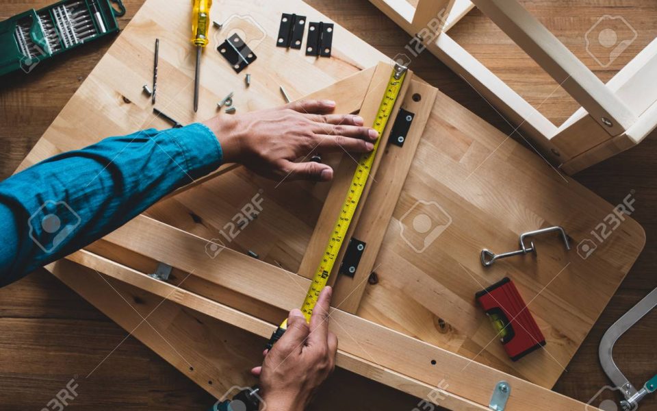 Man assembly wooden furniture,fixing or repairing house with yel Man assembly wooden furniture,fixing or repairing house with yellow tape measures.top view
